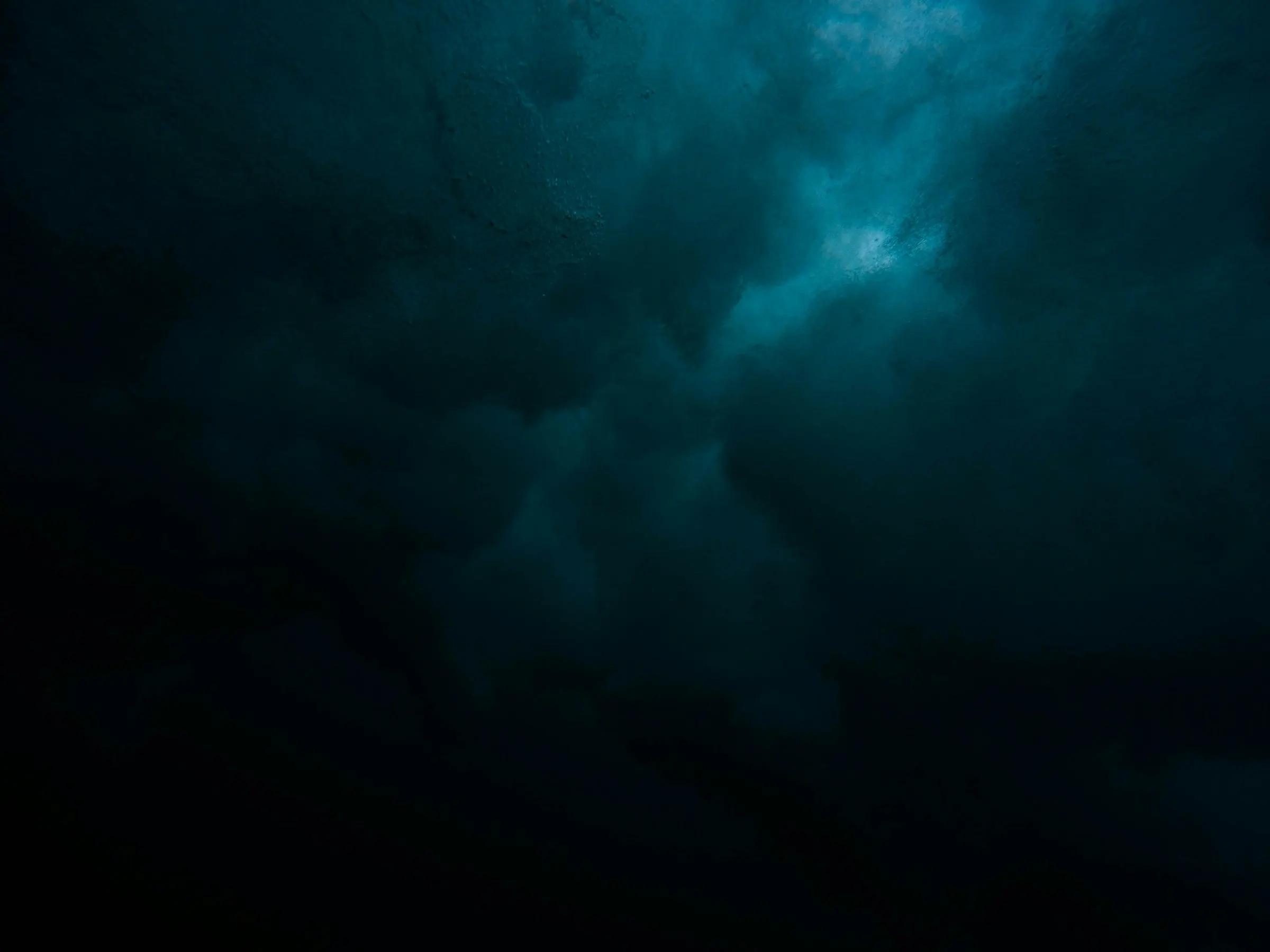A dark field of teal cloud lit faintly from behind, the light falling away into black.